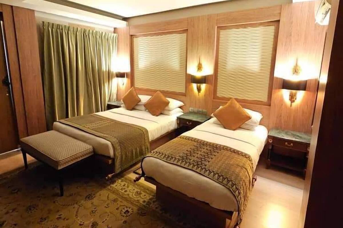 A hotel room with two beds, a small sofa, and a patterned carpet.
