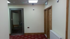 A hallway with patterned carpet, a door, and a radiator. - The Park Hotel (Bradford)
