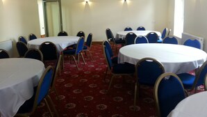 A conference room with round tables and blue chairs, carpeted floor, and ceiling lights. - The Park Hotel (Bradford)