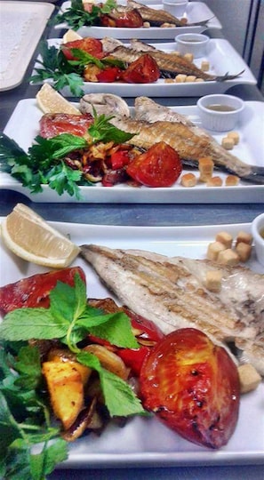 Une série d’assiettes garnies de poisson grillé, de tomates et d’herbes aromatiques.