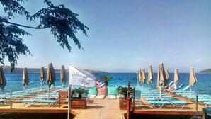A beachside pool area with lounge chairs and umbrellas, a wooden deck, and a flag for 'gökoy resort'. - Golkoy Suites Boutique Hotel (Bodrum)