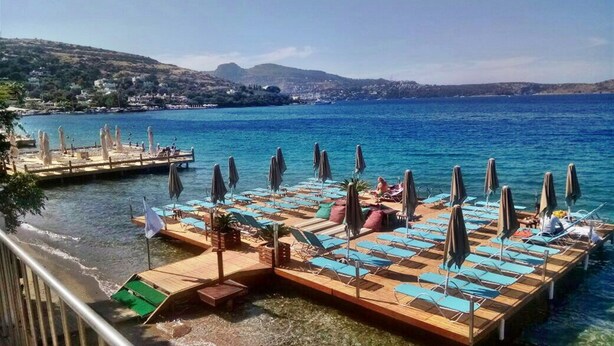 A seaside resort with a pool area, lounge chairs, and umbrellas. - Golkoy Suites Boutique Hotel (Bodrum)