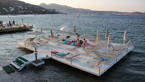 A floating platform with sun loungers and umbrellas, docked in calm waters with boats in the background. - Golkoy Suites Boutique Hotel (Bodrum)