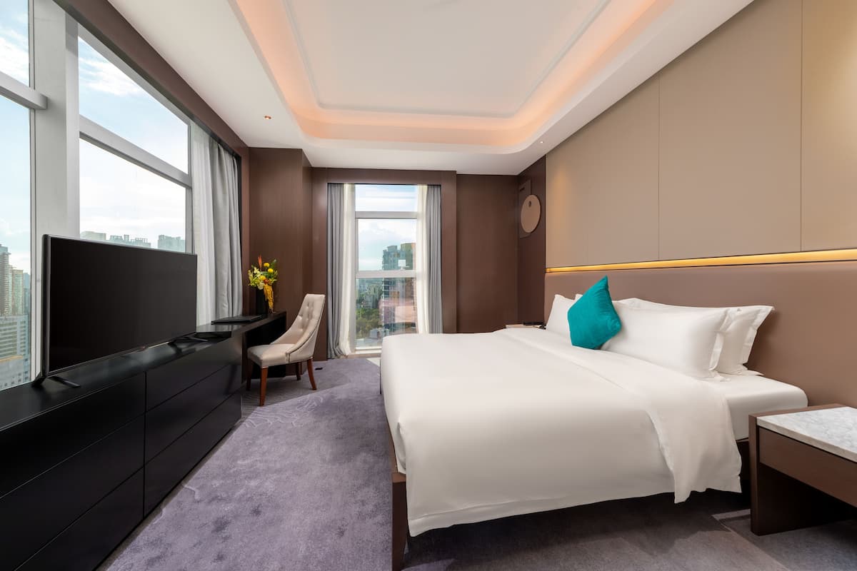 Habitación de hotel moderna con una cama grande, un televisor de pantalla plana, un escritorio y vistas a la ciudad.