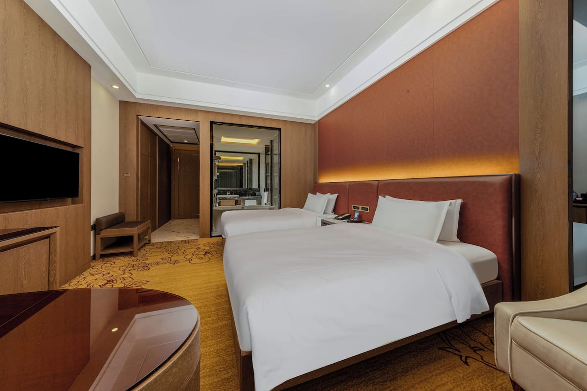 Una habitación de hotel con una cama grande, un escritorio, un televisor y un baño visible a través de una puerta abierta.