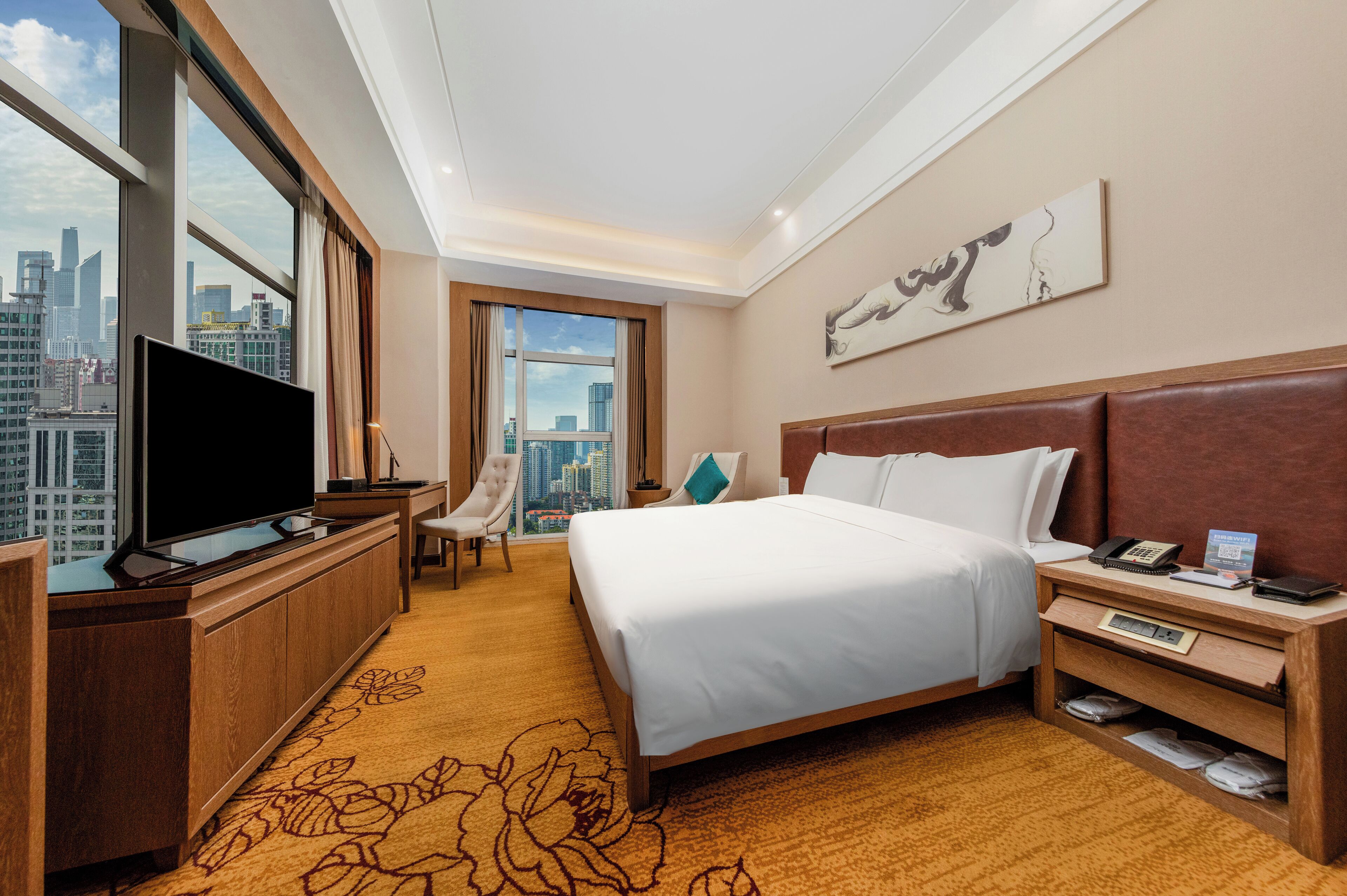 Habitación de hotel con una cama grande, televisión, escritorio y vistas a la ciudad.
