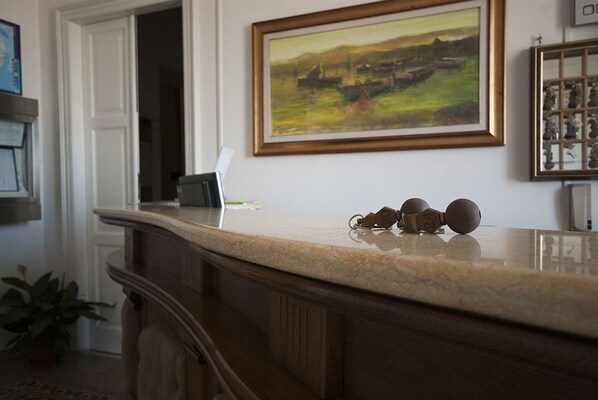 A reception area with a marble counter, a painting above it, and a framed picture on the wall. - Hotel AeR BJ Vittoria (Cagliari)