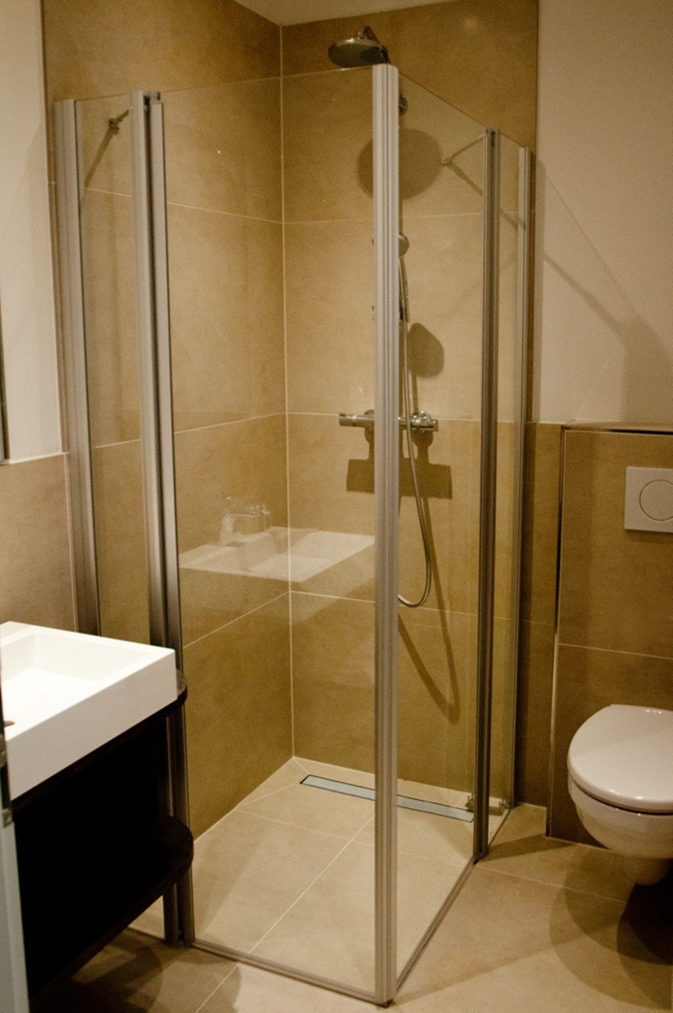 Une salle de bain moderne avec une douche à parois de verre, un lavabo blanc et des toilettes.