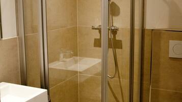 Une salle de bain moderne avec une douche à parois de verre, un lavabo blanc et des toilettes.