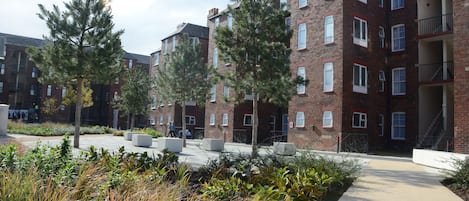 Un edificio de ladrillo de varios pisos con un patio central, rodeado de árboles y plantas.