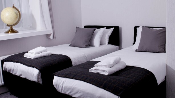 Ein Hotelzimmer mit zwei Betten, einem Globus auf einem Regal und einem Fenster mit Vorhängen.