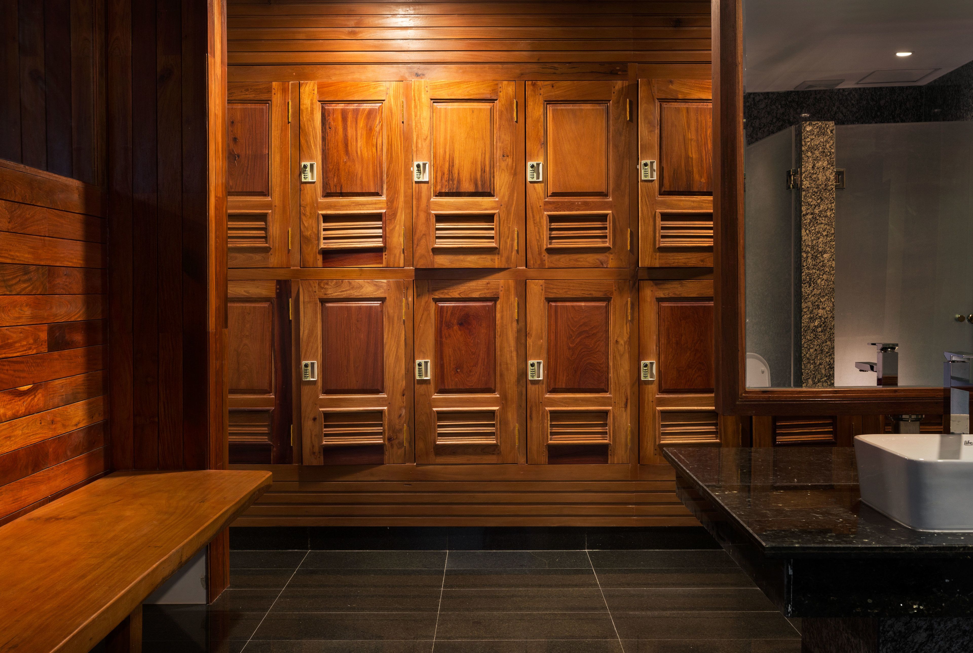 A wooden locker room with benches and a large mirror.