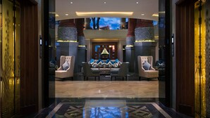 Eine geräumige Lobby mit hoher Decke, einer zentralen Sitzecke mit Sofas und Sesseln sowie einem großen, dekorativen Fenster.