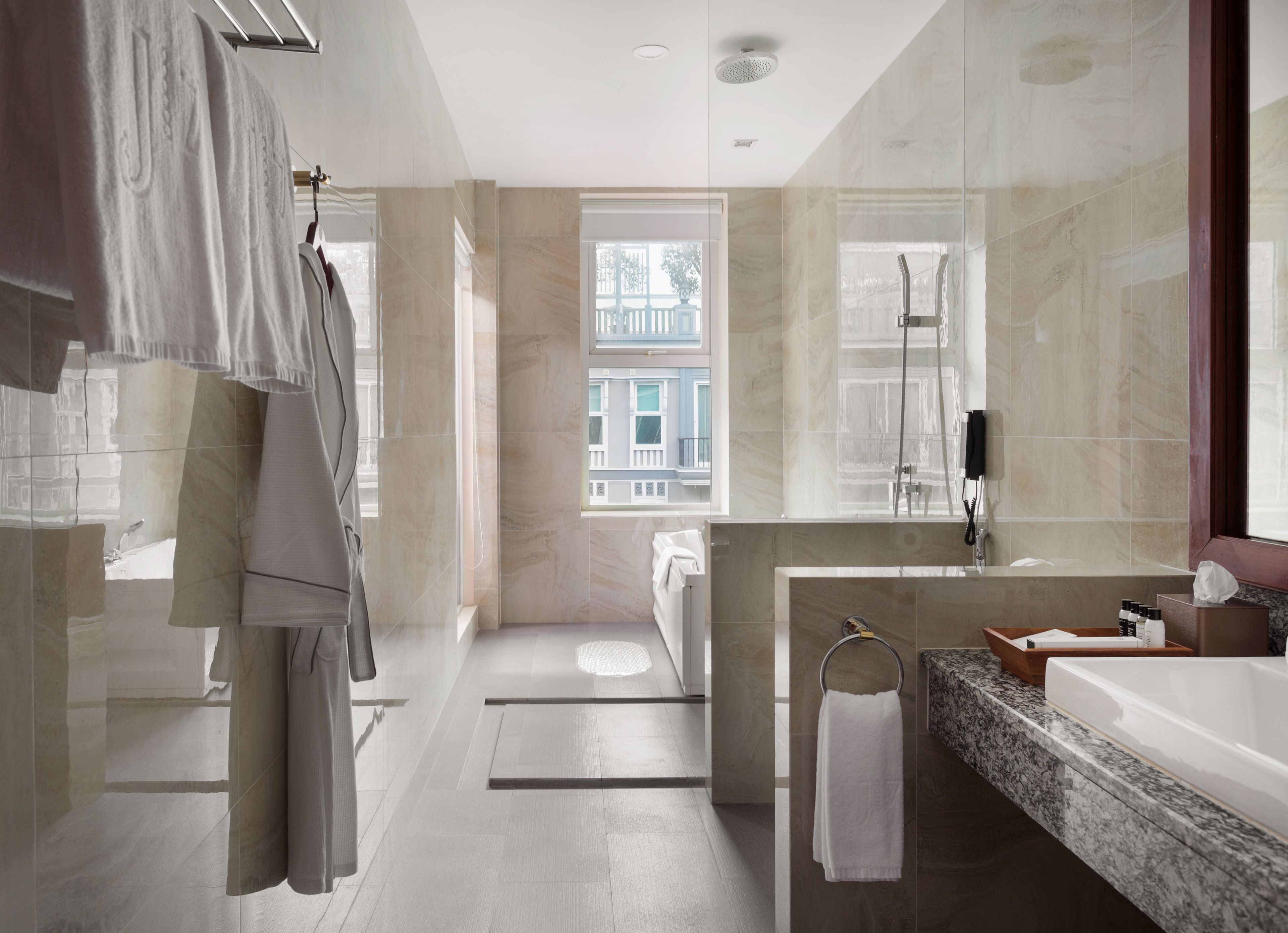 A modern bathroom with a large mirror, a bathtub, and a shower. There is a window providing natural light and a view of buildings outside.
