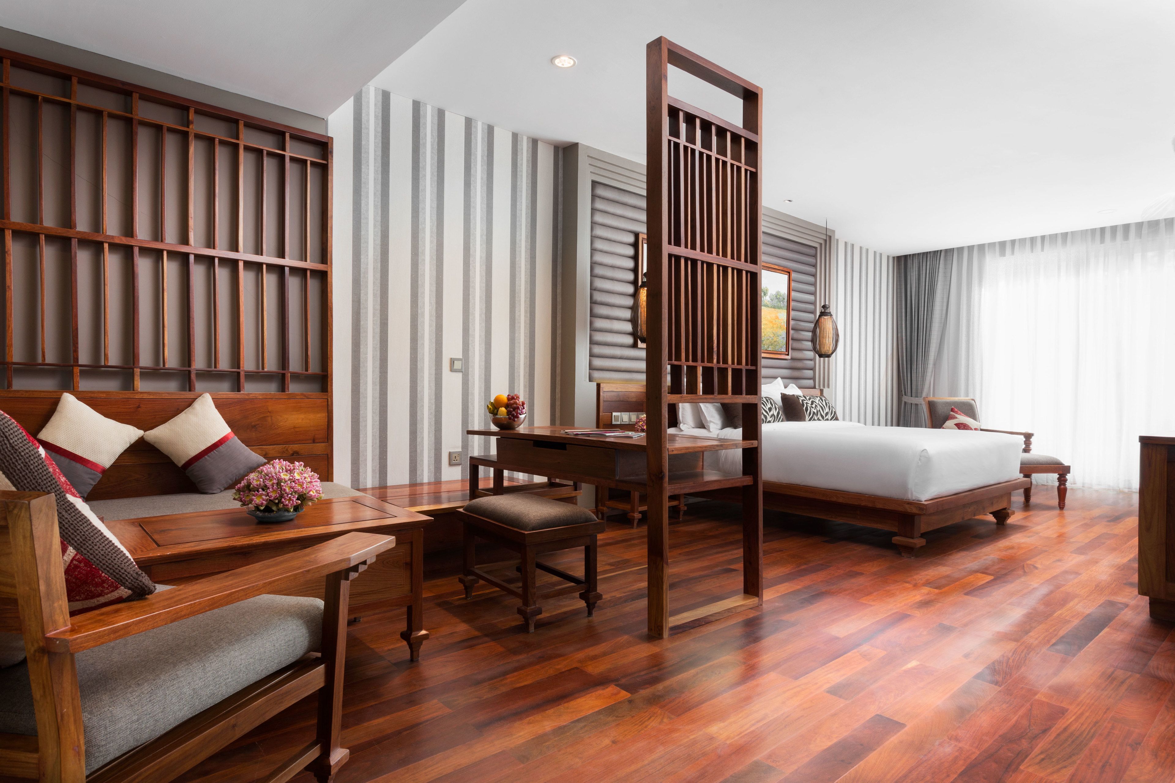 Une chambre d’hôtel avec un bureau en bois, un canapé, un lit et une grande fenêtre.