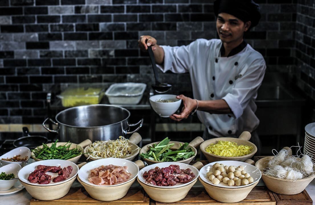 Un chef en una cocina con diversos ingredientes y utensilios de cocina.