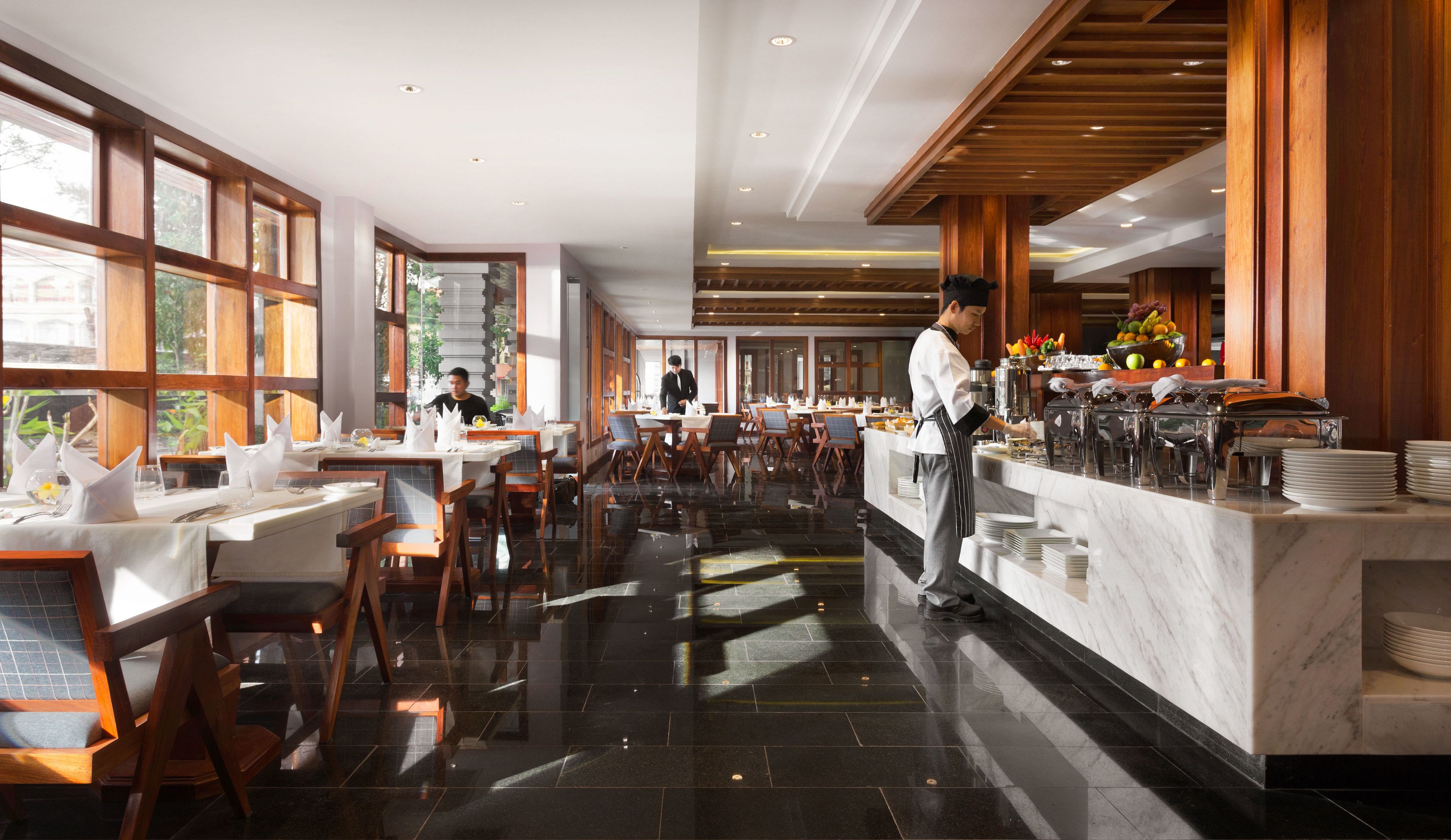 A spacious restaurant with high ceilings, large windows, and a polished marble floor.