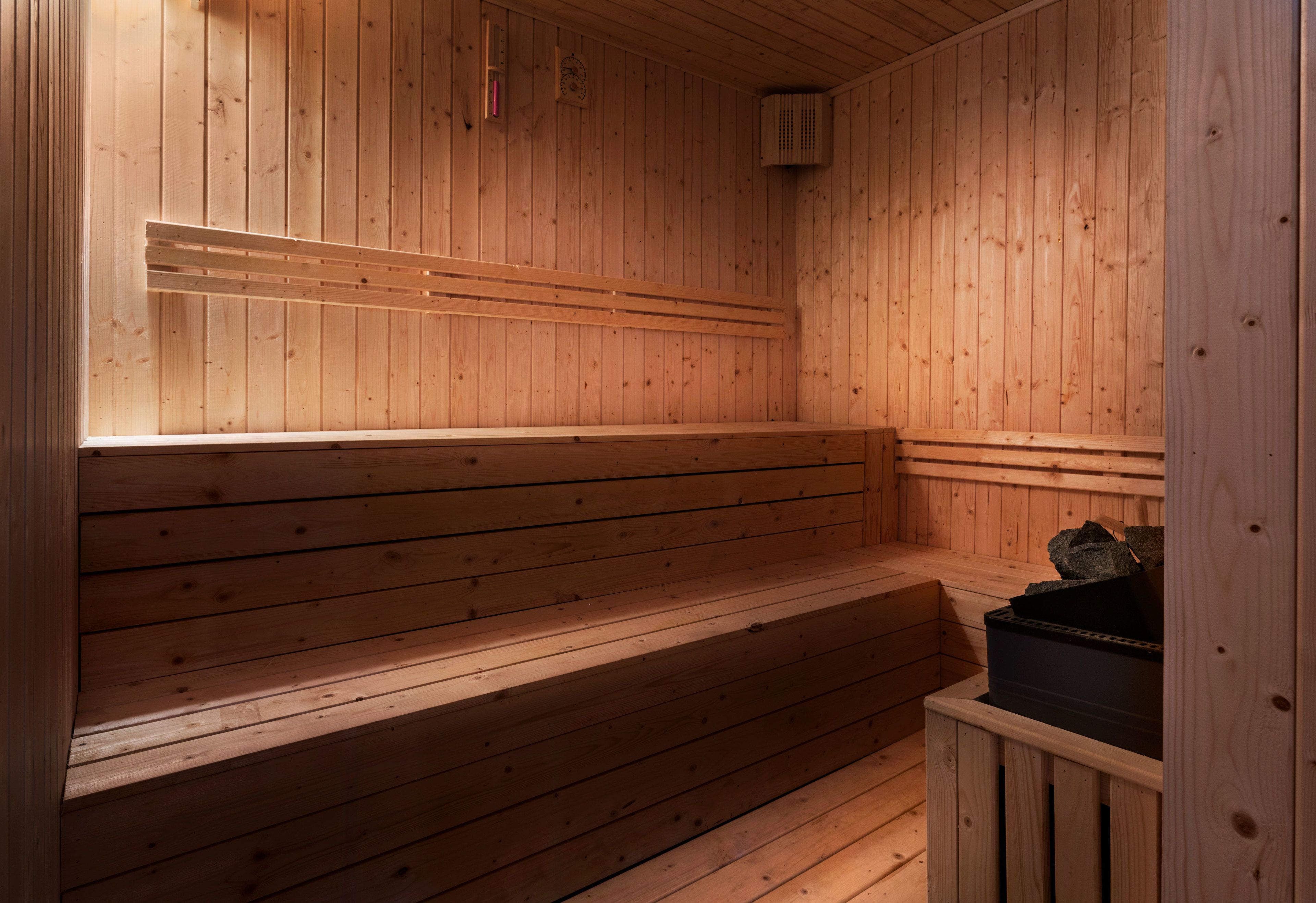 A wooden sauna with benches and a small heater.