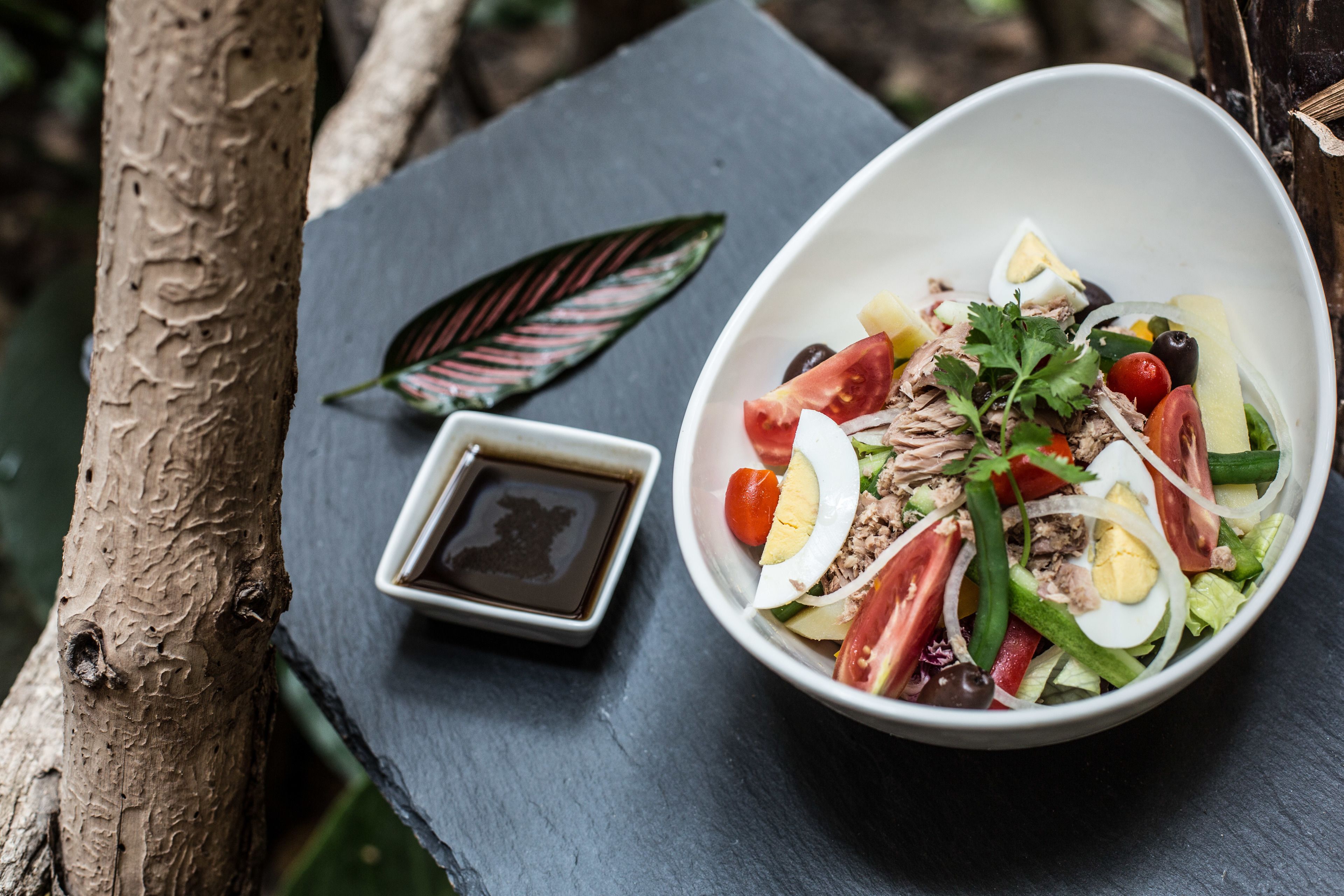 A bowl of salad with various ingredients on a slate table.