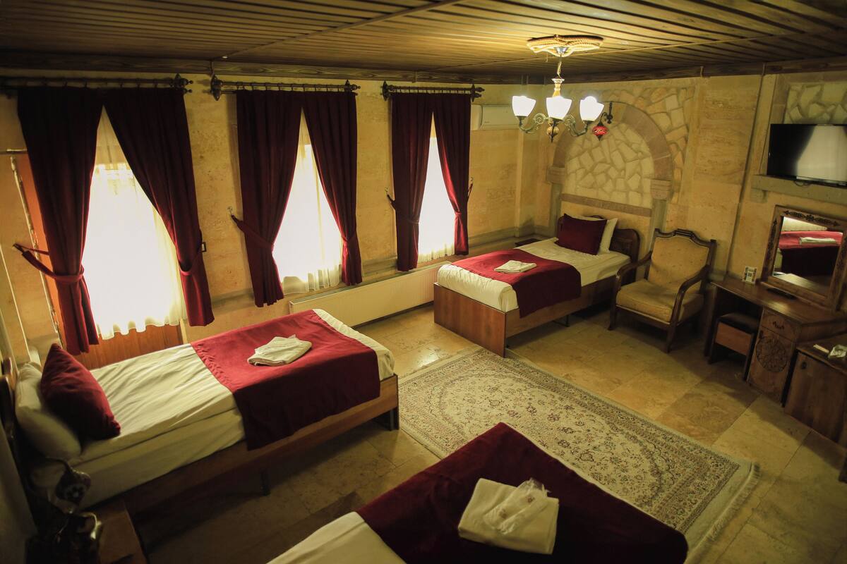 Habitación de hotel con dos camas, una silla, un televisor y una chimenea.