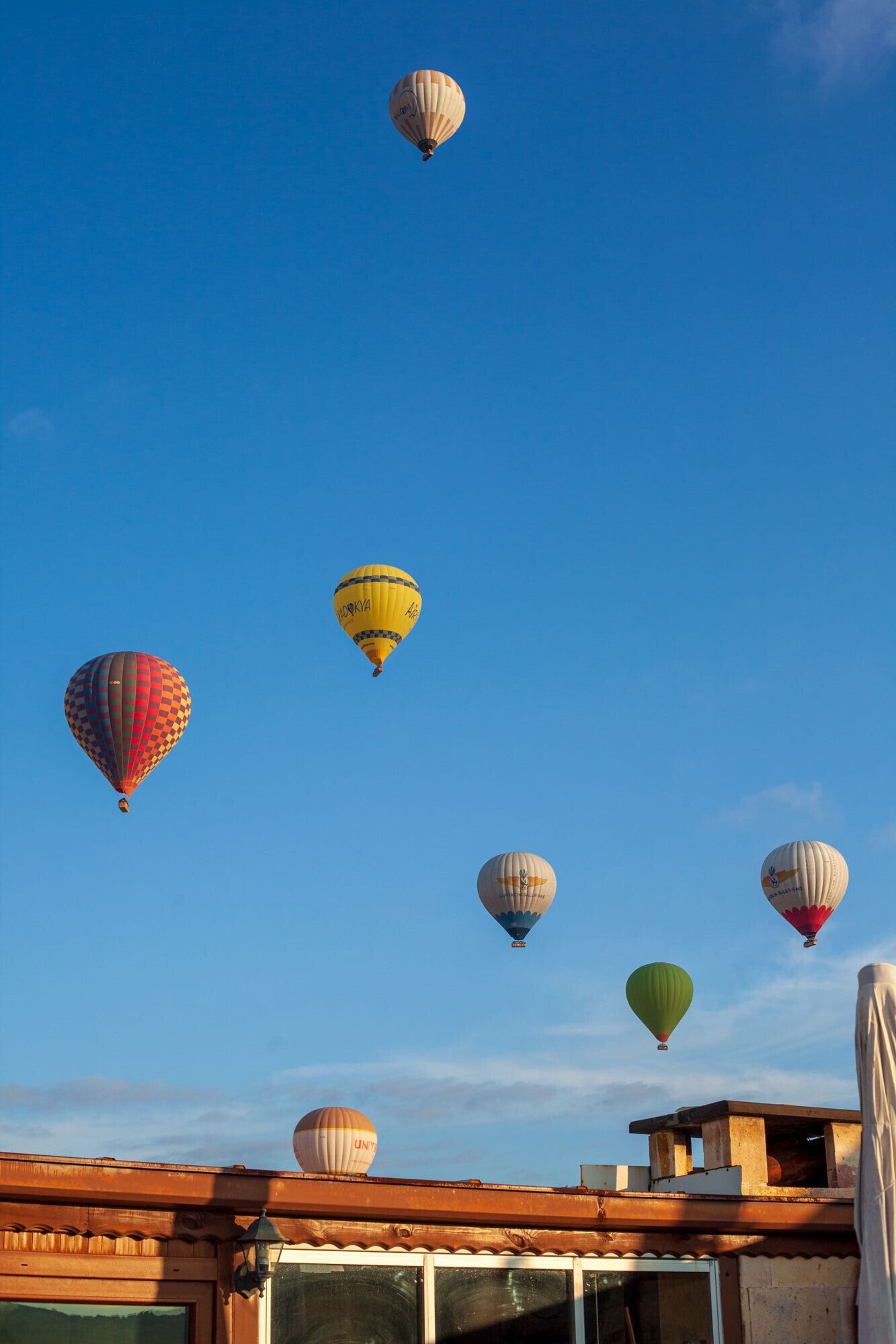 A clear blue sky with multiple hot air balloons of various colors and designs.