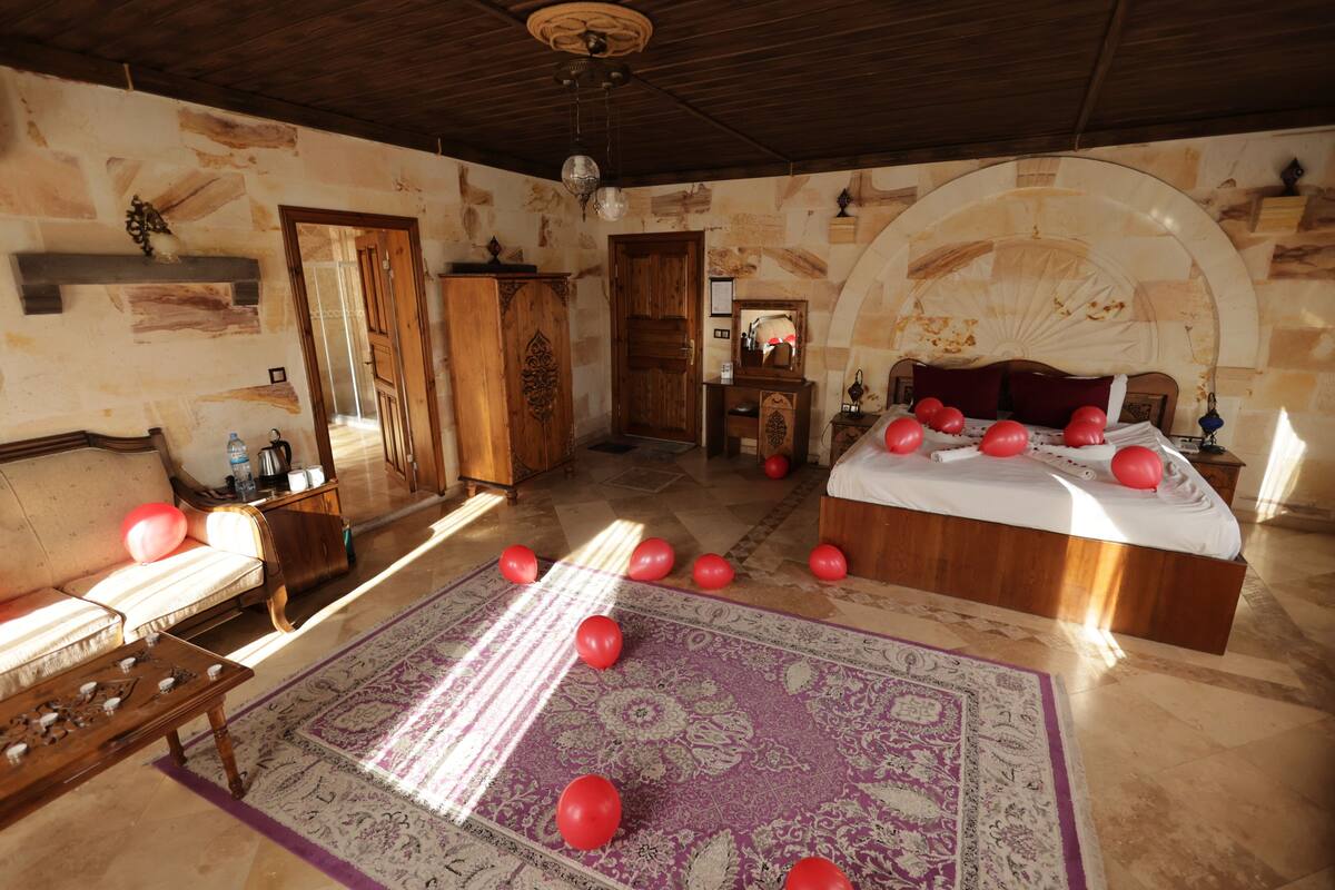 Una habitación con una cama, un sofá, un armario de madera, un espejo y una alfombra estampada.