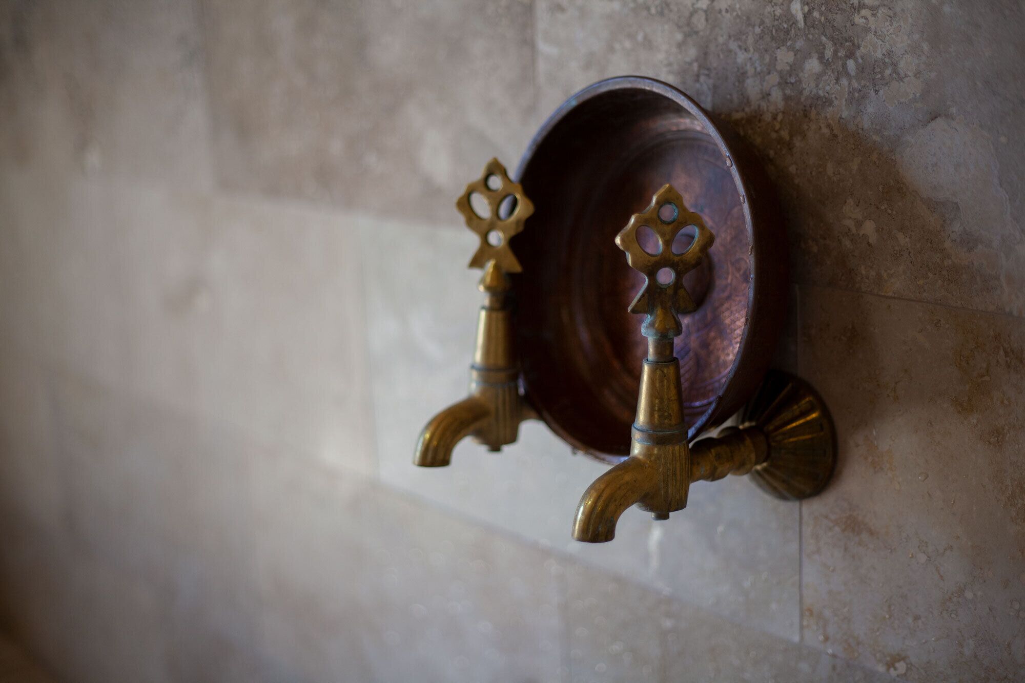 A wall-mounted brass faucet with a decorative plate.