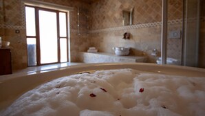 A bathroom with a bathtub filled with white foam, a sink, and a mirror on the wall.
