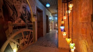 A corridor with a bicycle wheel, hanging decorative lights, and a mural on the wall.