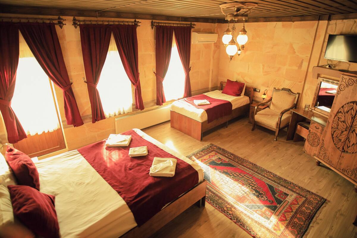 Habitación de hotel con dos camas, un sofá, una silla, un televisor y un tapete decorativo.