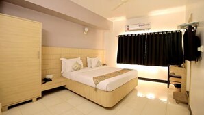 A hotel room with a bed, wardrobe, desk, and a ceiling fan.