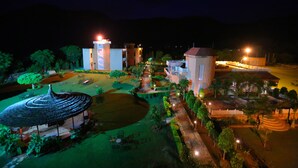 A well-lit courtyard with a central pavilion, surrounded by buildings with illuminated windows and a clear pathway. - Sariska Tiger Camp Resort (Alwar)
