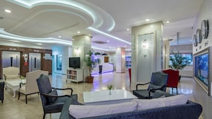 A modern lobby with seating, a reception desk, and a television. - May Flower Apart Hotel (Alanya)