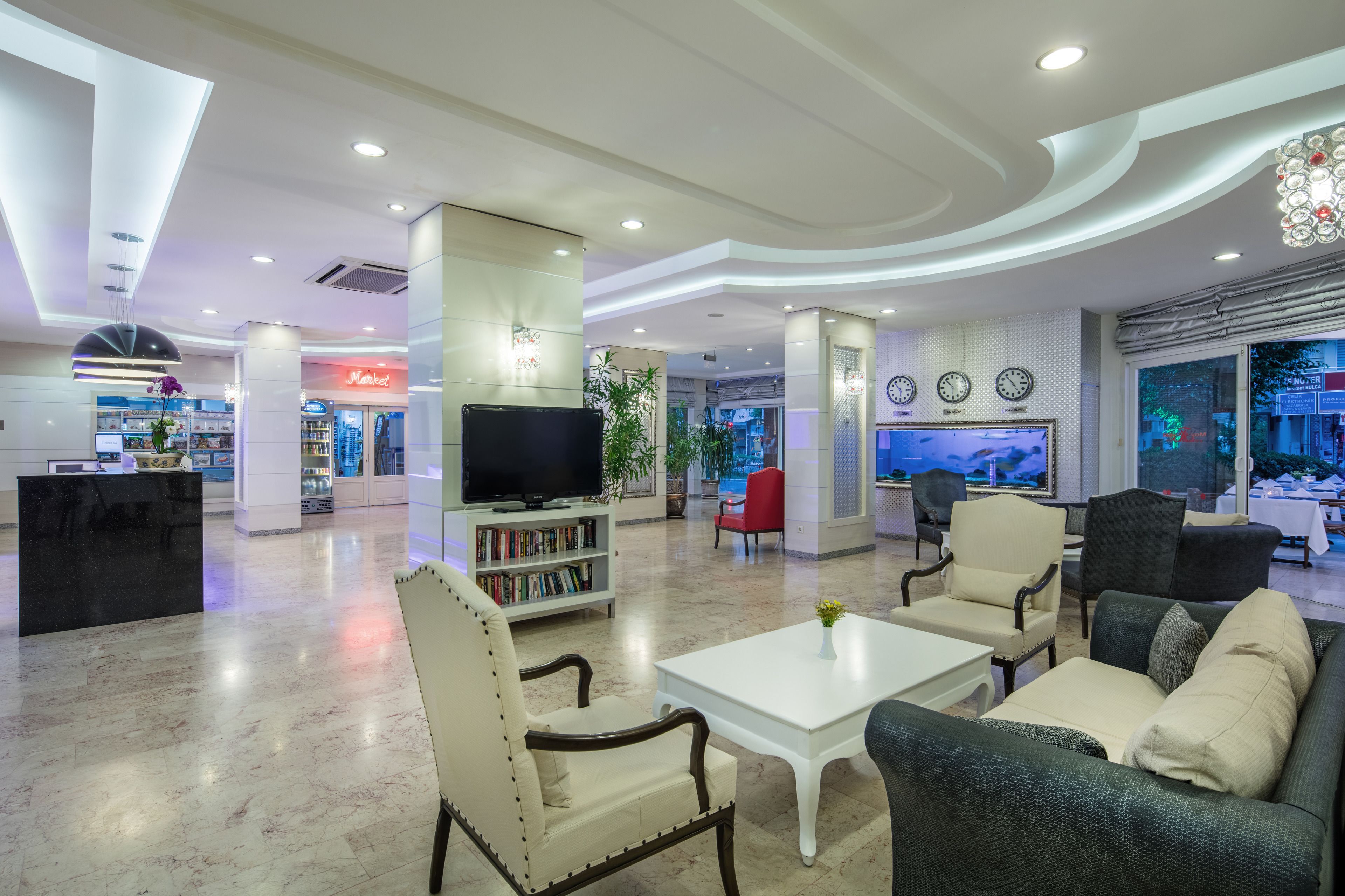 A spacious lobby with a reception desk, a television, a bookshelf, and comfortable seating areas.