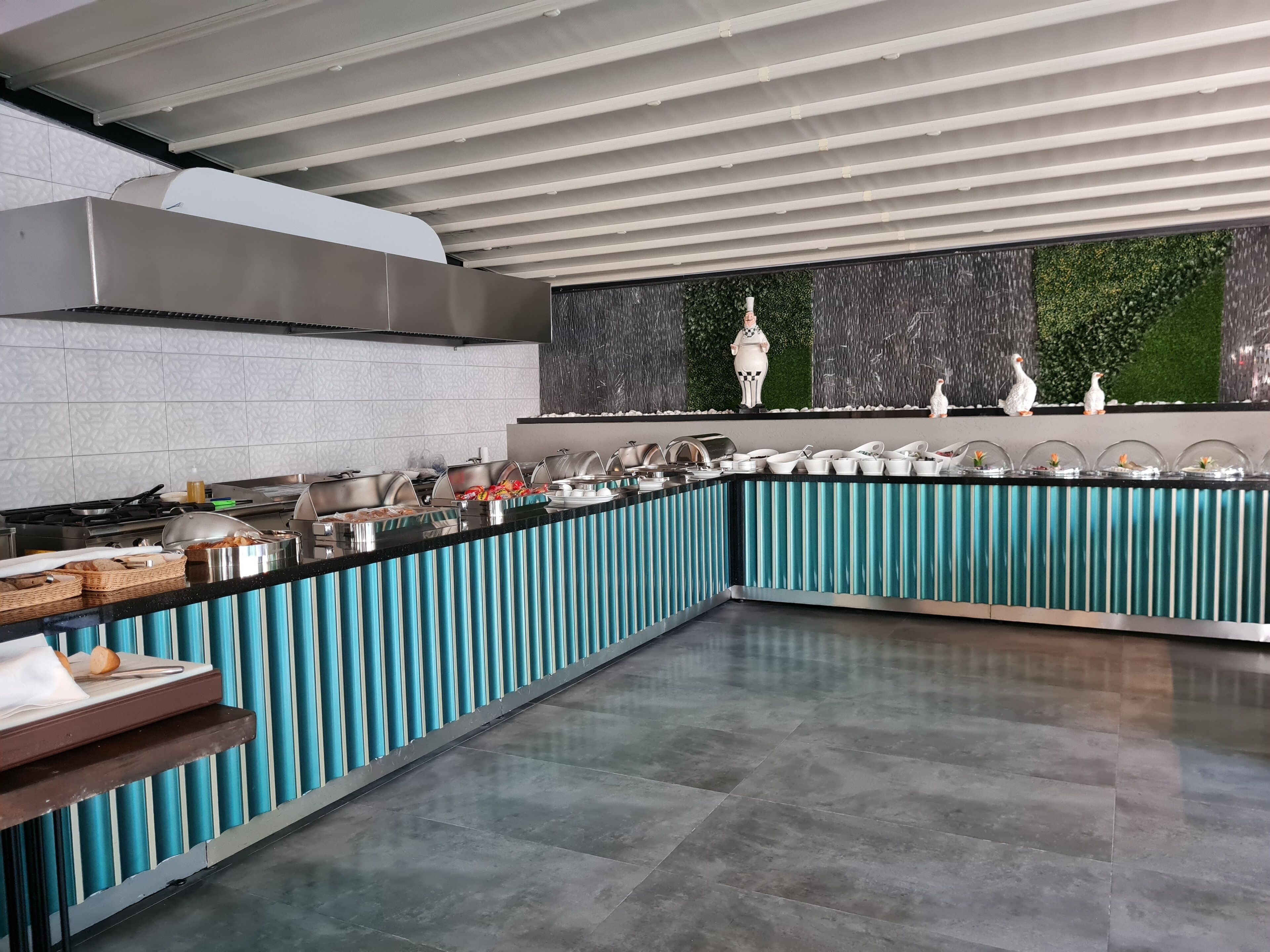 A modern kitchen with a curved island, stainless steel appliances, and a decorative wall with a waterfall feature.