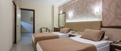 A hotel room with two single beds, a nightstand, a bedside table, a mirror, and a door leading to a hallway.