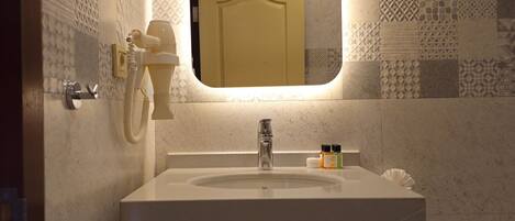 A bathroom with a sink, mirror, towel rack, and a trash bin.