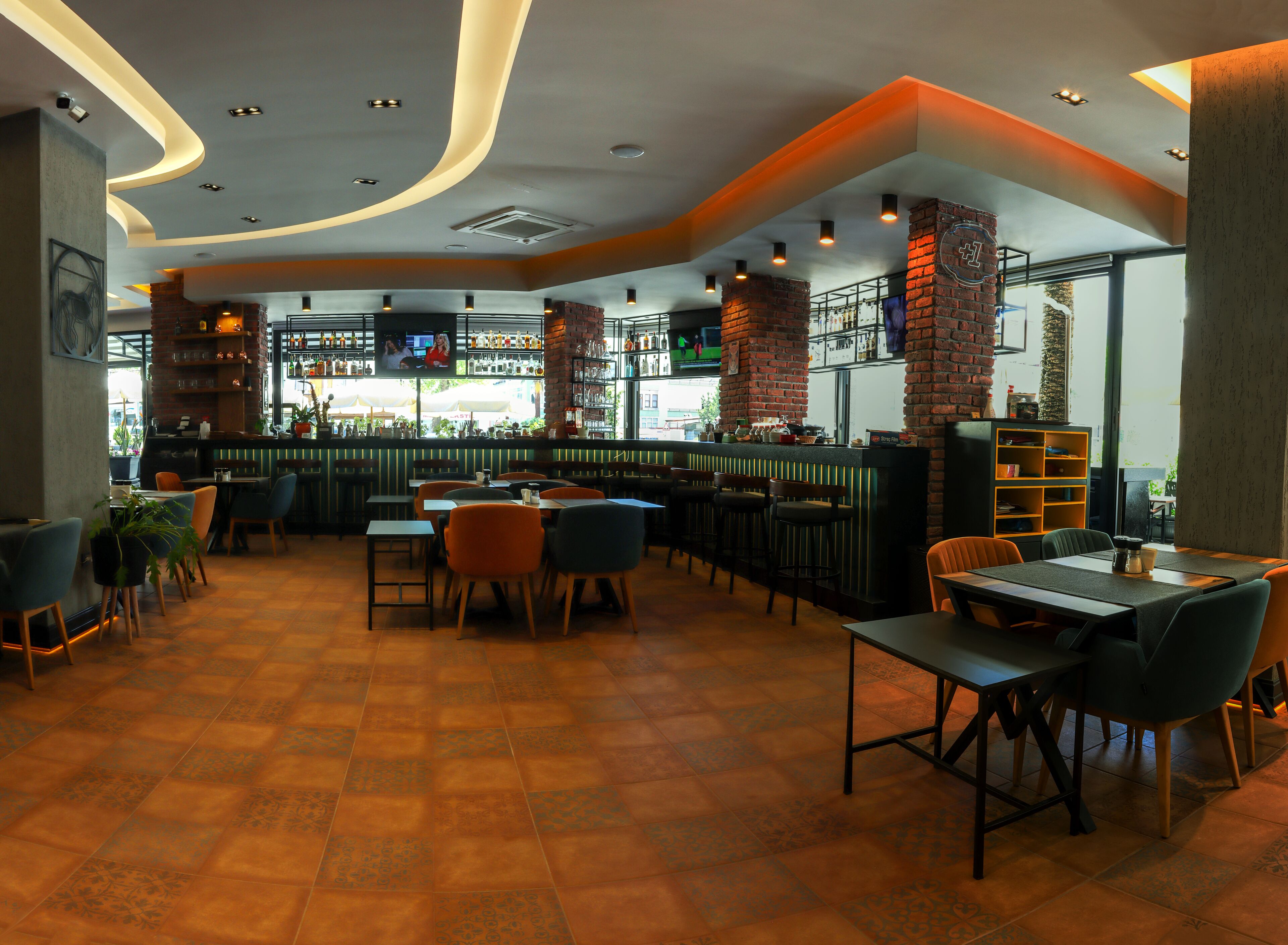 A restaurant interior with a bar area, seating arrangements, and a television screen.