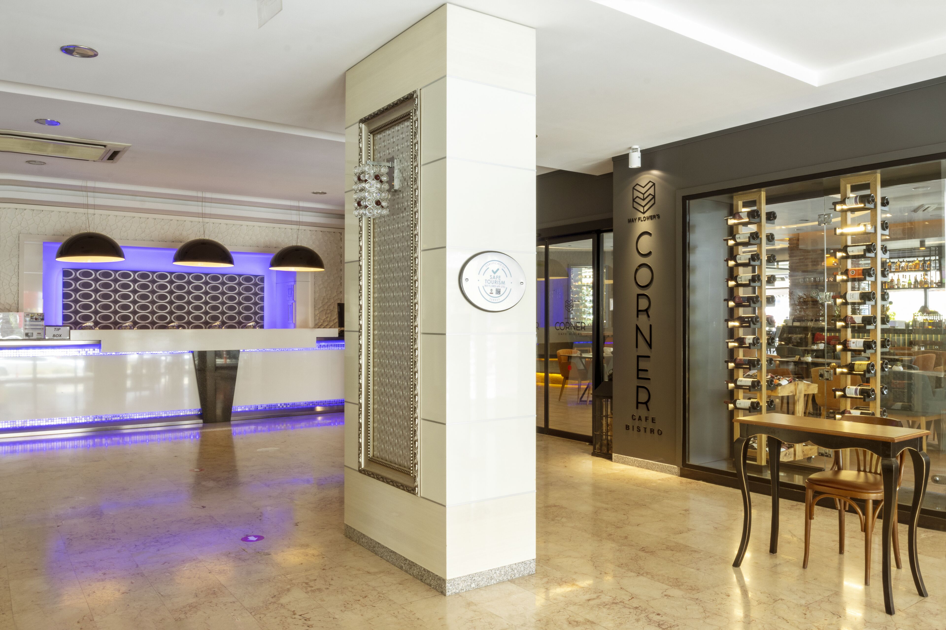 Un moderno vestíbulo de hotel con una recepción, un panel decorativo y una exhibición de vinos.