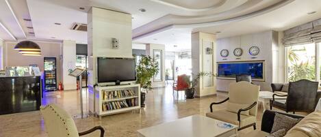 A spacious lobby with a flat-screen TV, a bookshelf, and comfortable seating areas.