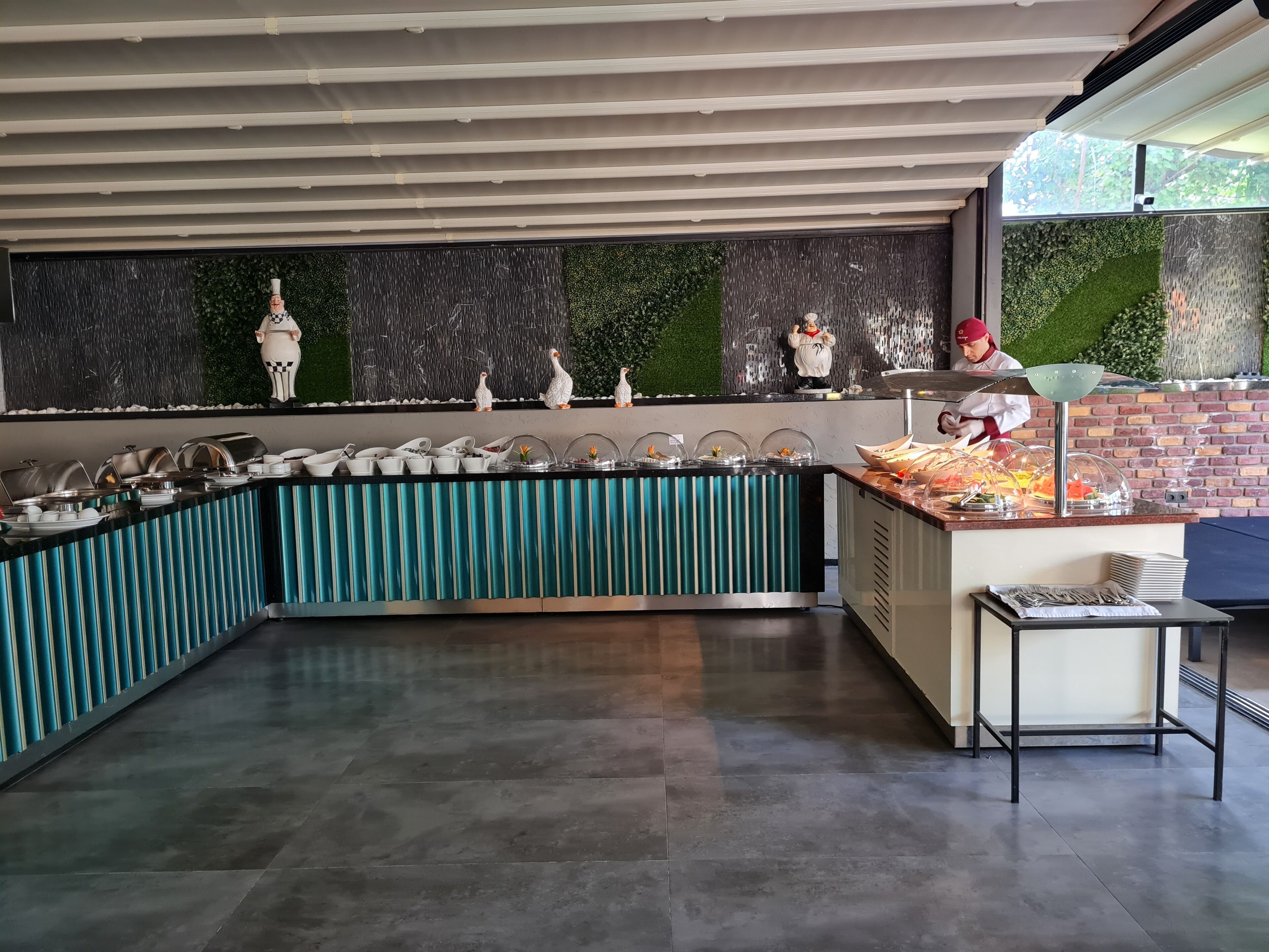 A buffet area with a curved counter, food display cases, and a chef preparing food.