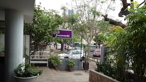 Una entrada empedrada con plantas en macetas, un letrero que dice 'Jacaranda' y un estacionamiento con coches.