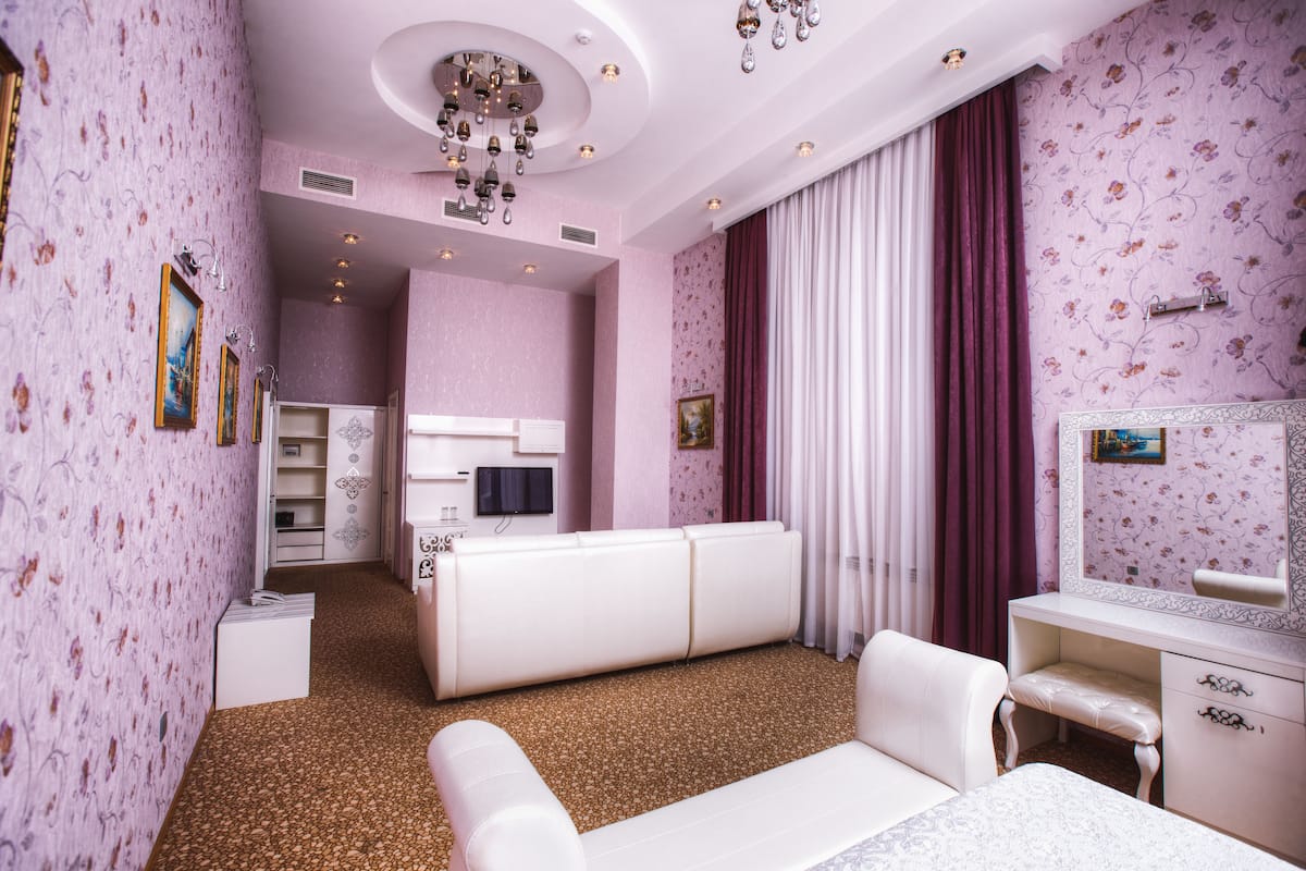 Un dormitorio en tonos rosas con un sofá blanco, un escritorio y una cama.