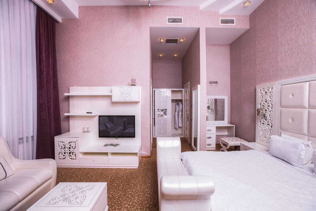 Una habitación de hotel moderna con una cama grande, televisión, tocador y una zona de estar.