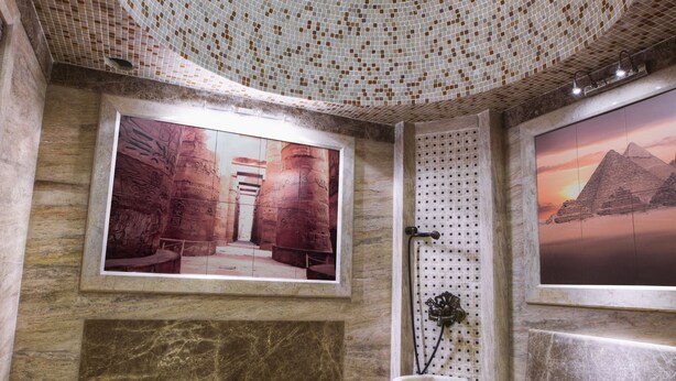 A bathroom with a mosaic dome ceiling, a framed picture of ancient ruins, a shower area, and a large window with a sunset view. - Admiral Hotel Baku (Baku)