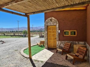 A rustic building with a stone archway and a wooden door, outdoor seating with benches, and a clear view of the surrounding landscape.