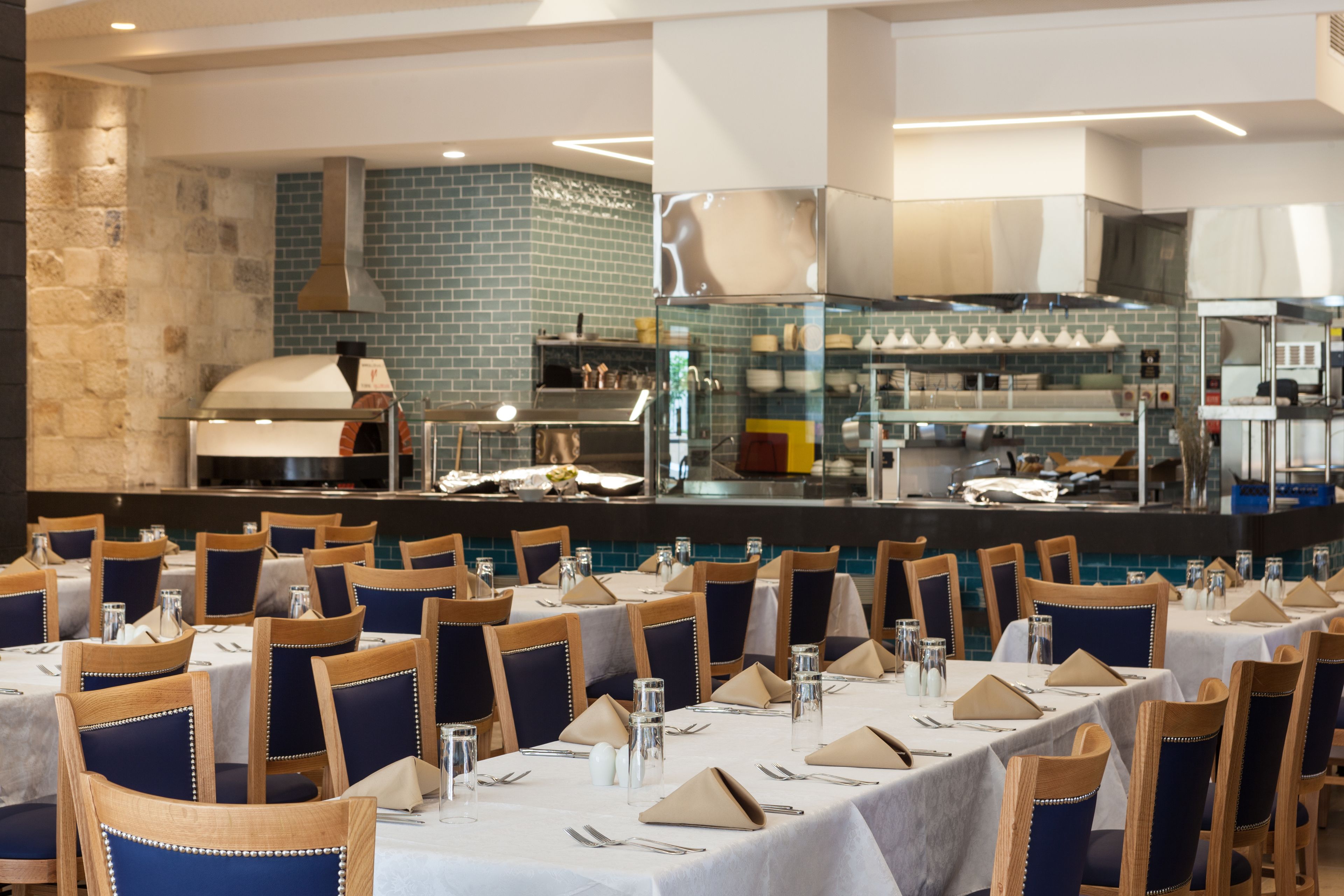 Ein Restaurant mit mehreren Tischen und Stühlen, einer Küchenzeile und einer Steinwand.