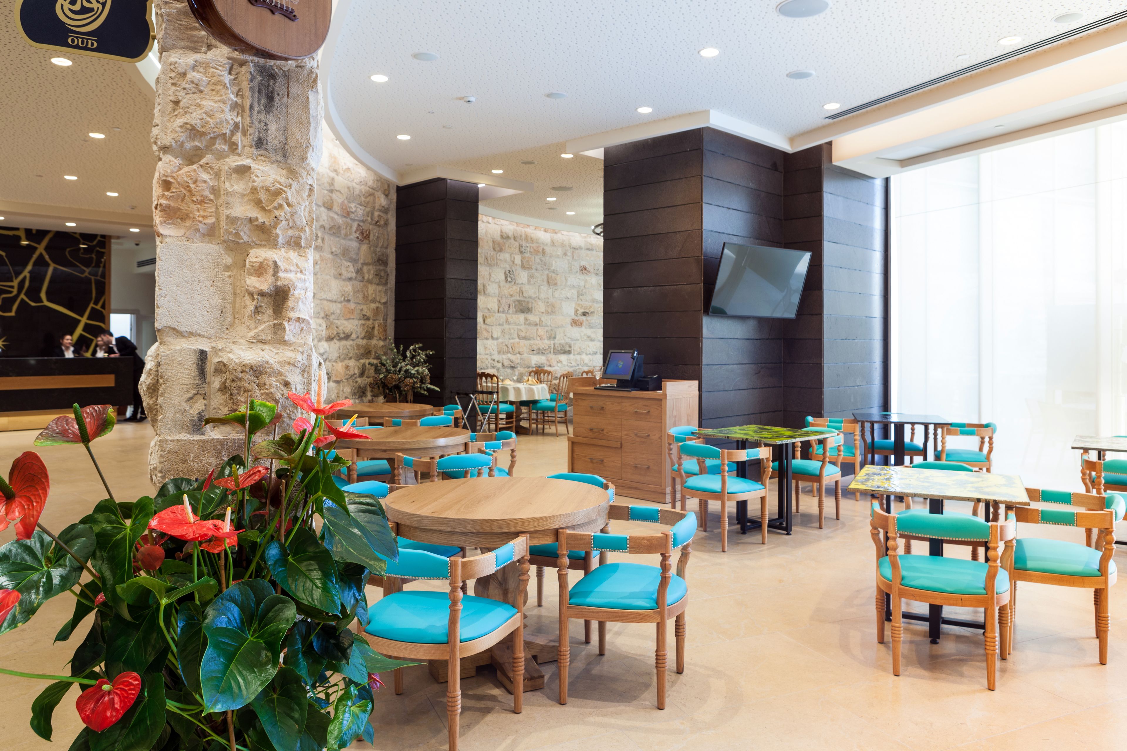 Un restaurante con mesas y sillas de madera, un pilar de piedra y un televisor montado en la pared.
