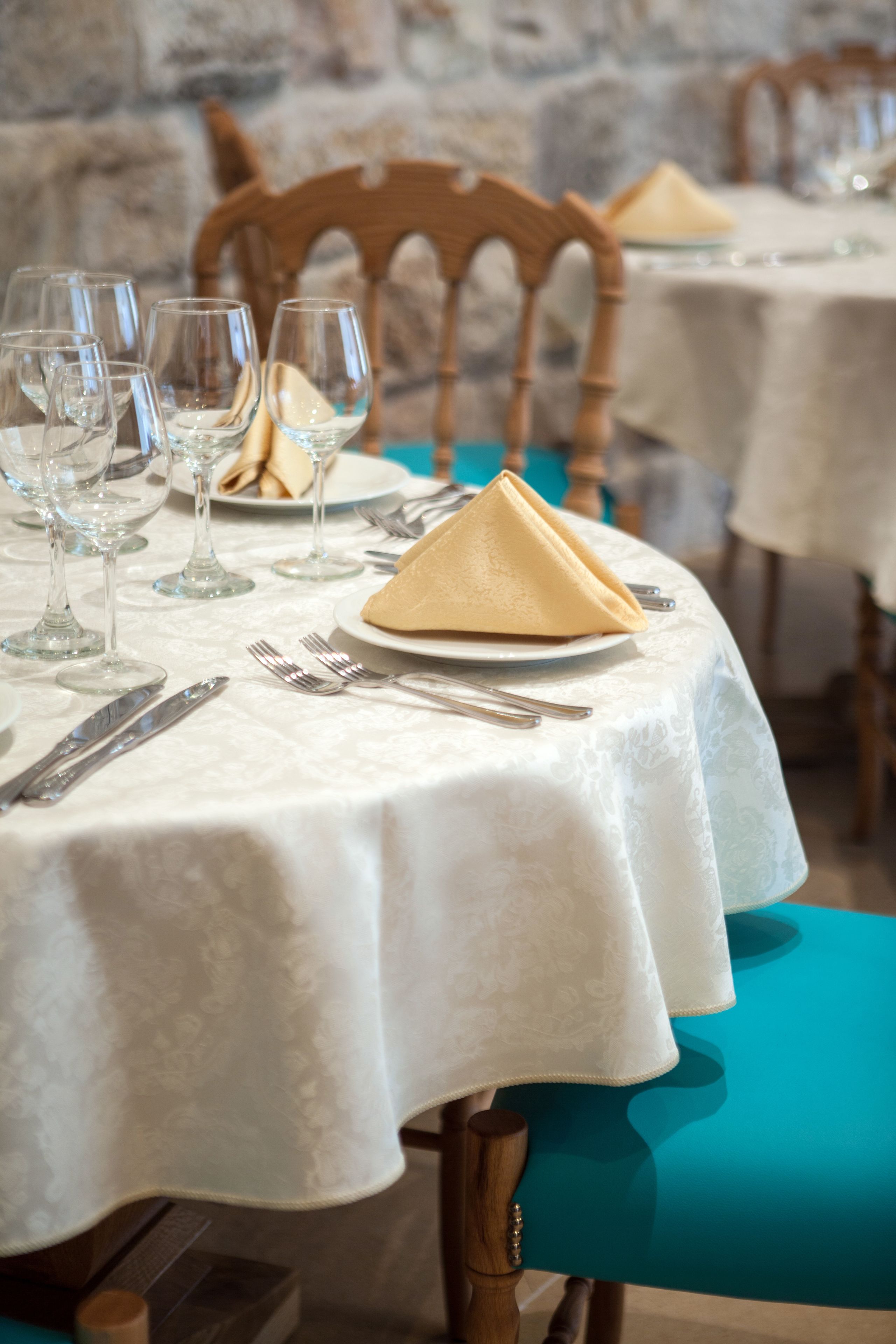 A dining table set with wine glasses, plates, and cutlery.