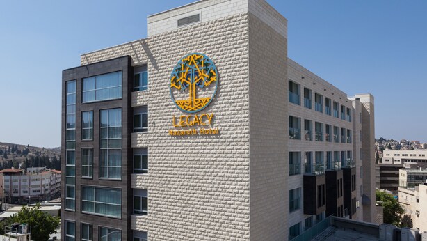 A hotel building with a prominent logo and the name "Legacy" on the facade. - Legacy Nazarethe Hotel (Nazareth)